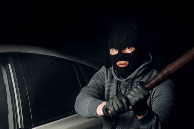 Bir Balaclava soyguncu bir baseba ile araba cam kırmaya çalışır