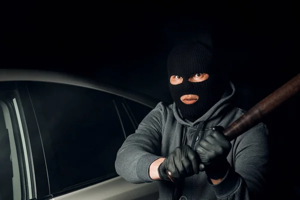 Bir Balaclava soyguncu bir baseba ile araba cam kırmaya çalışır