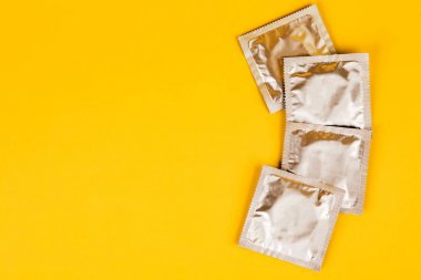 Сondom sarı bir arka plan üzerinde. Güvenli seks kavramı.