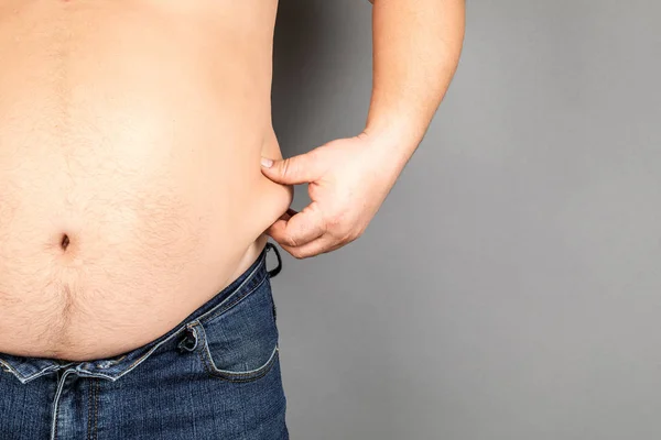 Толстяк, проверяя свой вес, на сером фоне — стоковое фото