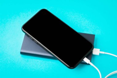 Mavi backgr üzerinde Usb kablosu üzerinden Power Bank ile şarj akıllı telefon