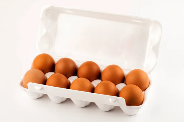 Huevos marrones en paquete de plástico sobre fondo blanco . — Foto de Stock