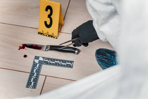 Криминалист на месте преступления, записывает и проверяет
