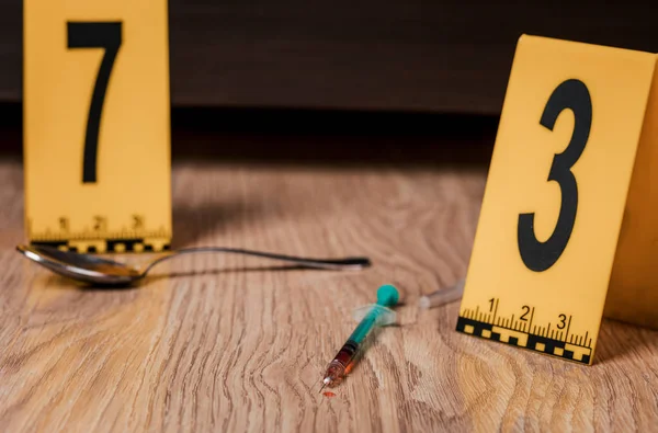 A drug syringe next to a police sign on the floor of the house. — Stock Photo, Image