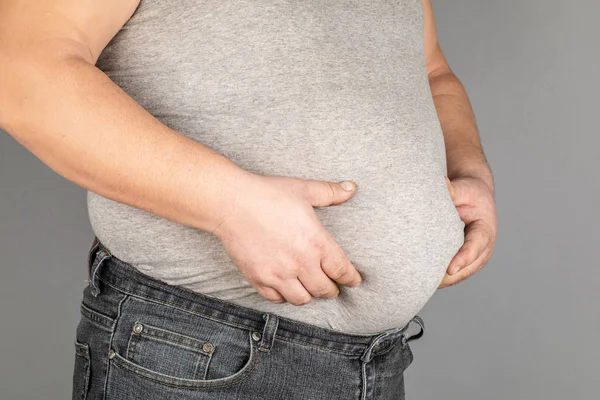 Homem gordo, verificando seu peso, em um fundo cinza — Fotografia de Stock