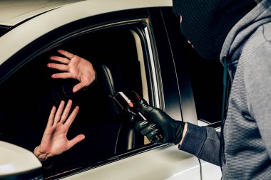 Elinde kırık bir şişeyle soyguncu maskesi takan bir adam.