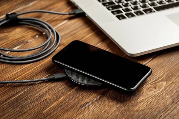 Wireless charging lies next to the computer on a stylish wooden