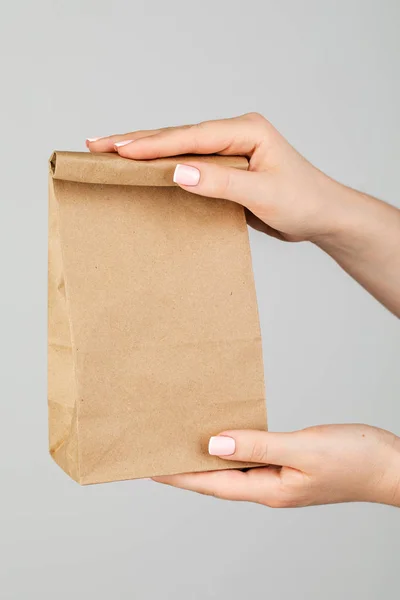 Close - up of a woman holding a brown empty paper bag isolated o — Stock Photo, Image