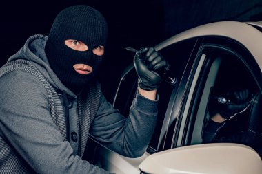 Siyah maskeli bir soyguncu, dri 'ye el feneri doğrultuyor.