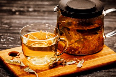 Ahşap masa üzerinde ıhlamur ile çay cam fincan.