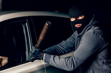 Bir Balaclava soyguncu bir baseba ile araba cam kırmaya çalışır