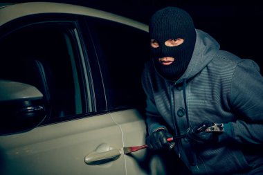 erkek hırsız bir levye ile araba kapısını açmak için gidiyor.