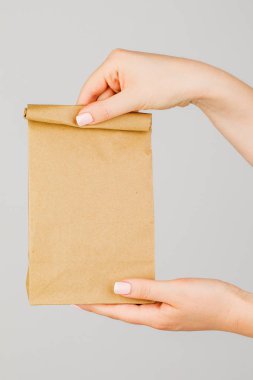 Whit 'te kahverengi boş kese kağıdı tutan kadının yakın çekimi.