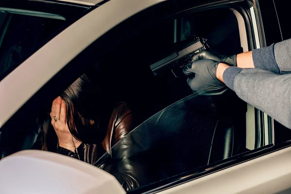 Silahlı maskeli bir soyguncu arabadaki bir kadını tehdit ediyor. Soyguncu