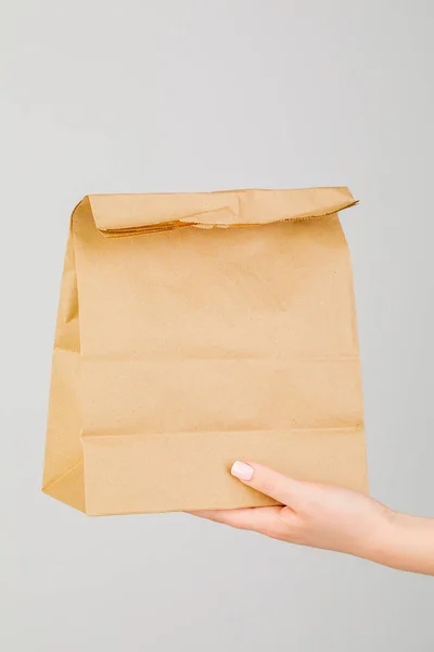 Close-up of woman holding brown empty paper bag isolated on whit — Stock Photo, Image