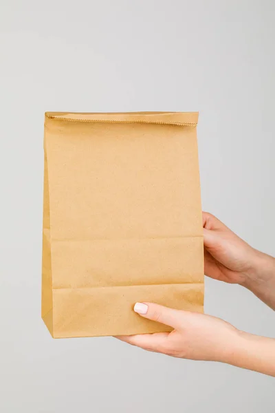 Крупный план женщины, держащей коричневый пустой бумажный пакет, изолированный на Уит — стоковое фото