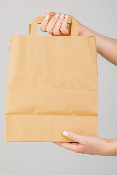 Close-up of woman holding brown empty paper bag isolated on whit — Stock Photo, Image