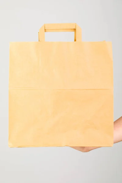 Close-up of woman holding brown empty paper bag isolated on whit — Stock Photo, Image