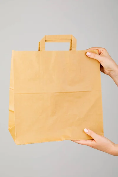 Close-up of woman holding brown empty paper bag isolated on whit — Stock Photo, Image