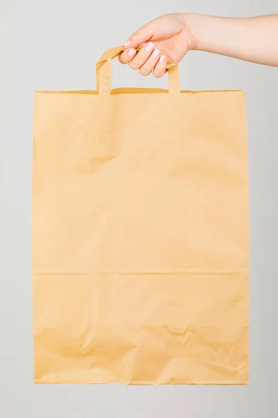 Close - up of a woman holding a brown empty paper bag isolated o — Stock Photo, Image