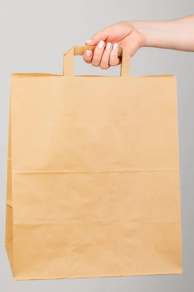 Close - up of a woman holding a brown empty paper bag isolated o — Stock Photo, Image