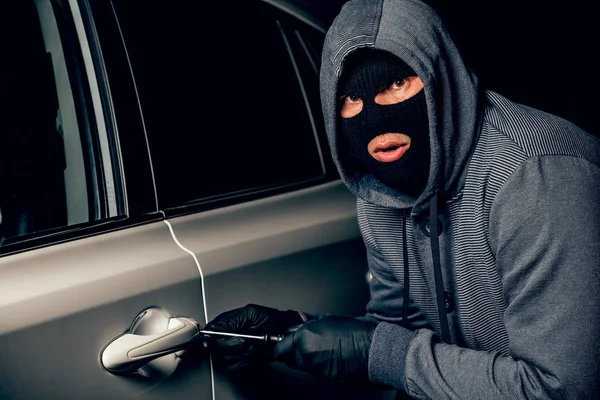 A man with a Balaclava on his head tried to break into the car. Stock Image