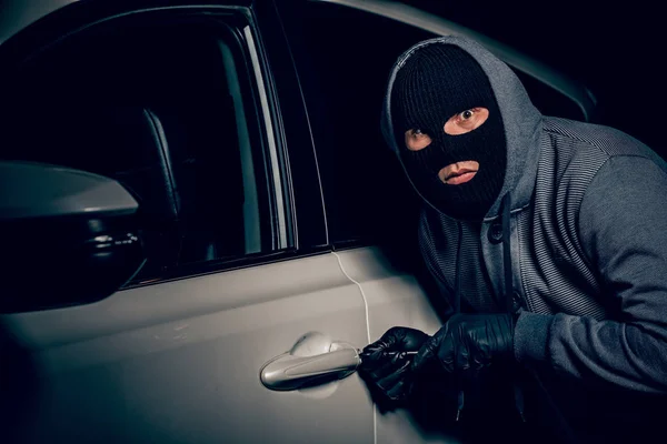 A man with a Balaclava on his head tried to break into the car. Stock Photo