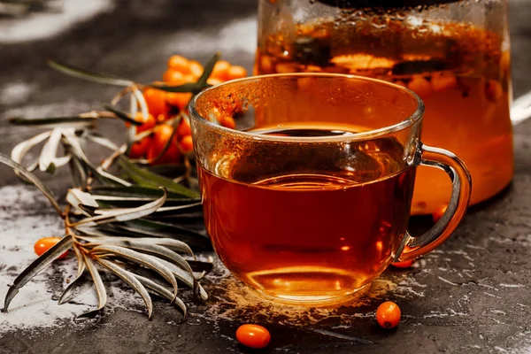 hot spicy tea with sea buckthorn in a glass teapot and Cup, on a