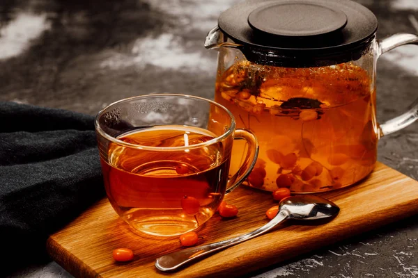hot spicy tea with sea buckthorn in a glass teapot and Cup, on a