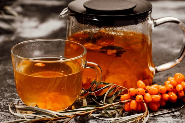 hot spicy tea with sea buckthorn in a glass teapot and Cup, on a