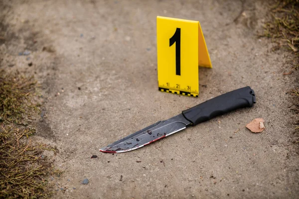 Crime scene investigation, bloody knife with crime markers on th — Stock Photo, Image