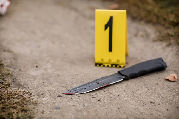 Crime scene investigation, bloody knife with crime markers on th — Stock Photo, Image