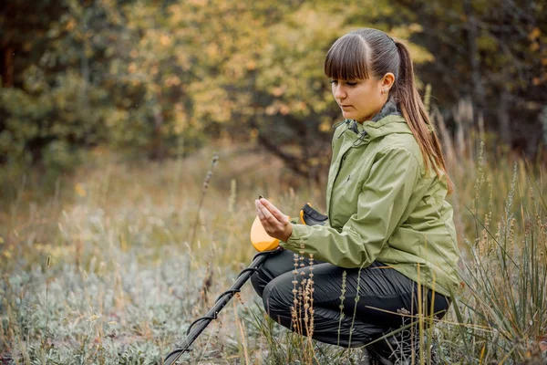 Young girl looks at the monitor of a metal detector on the backg — Stock Photo, Image