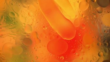 Su yüzeyindeki yağ damlacıklarının hareketine yakın çekim. Su yüzeyindeki yağ damlalarının renkli ve soyut makro arkaplanı