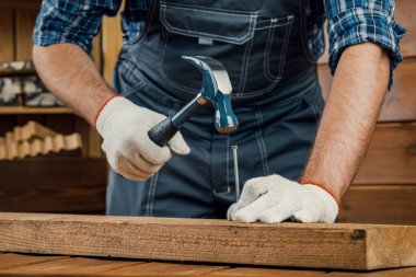 Bir adam, tahtaya çivi çakan bir marangozdur. Yenileme ve inşaat konsepti