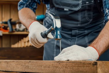 Bir adam, tahtaya çivi çakan bir marangozdur. Yenileme ve inşaat konsepti