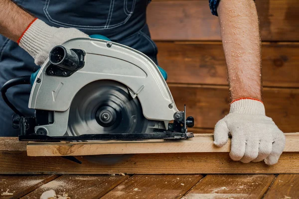 A male carpenter using an electric saw to cut a Board. The concept of renovation and construction