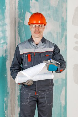 Mühendis, mimar ve müfettiş olan bir kişi, konut inşaatı projelerini izlemek, planlamak ve denetlemek için bir inşaat sahasında çalışır.