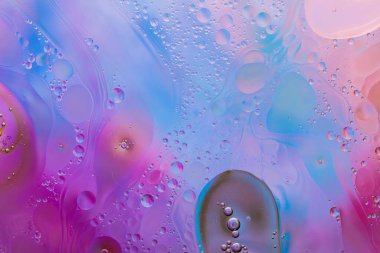 Su yüzeyindeki yağ damlacıklarının hareketine yakın çekim. Su yüzeyindeki yağ damlalarının renkli ve soyut makro arkaplanı