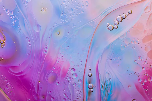Close-up of the movement of oil droplets on the water surface. Colorful abstract macro background of oil drops on the water surface