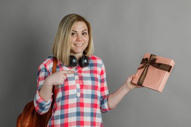 Şirin sarışın bir kızın stüdyo portresi, bir öğrenci, ekose gömlekli bir hediye / hoş bir sürpriz, kutuda bir hediye, neşeli bir sevinç, Sevgililer Günü.