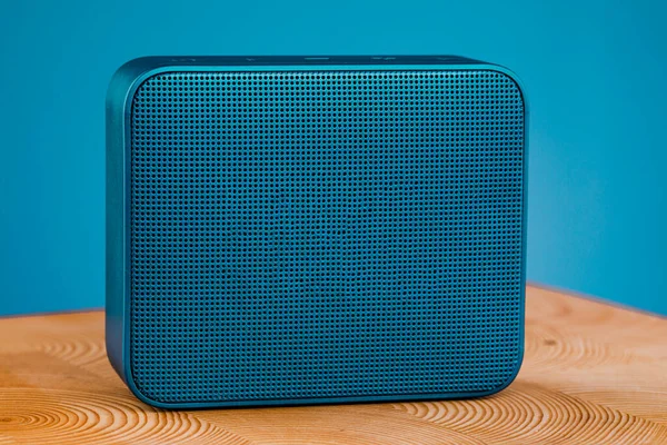 Portable blue wireless speaker, on a wooden table on a blue background
