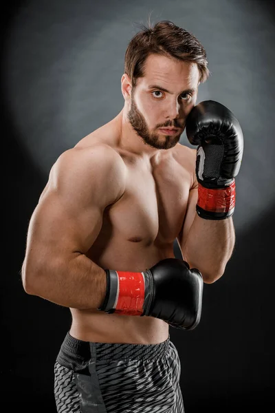 A man in Boxing gloves. A man Boxing on a black background. The concept of a healthy lifestyle.