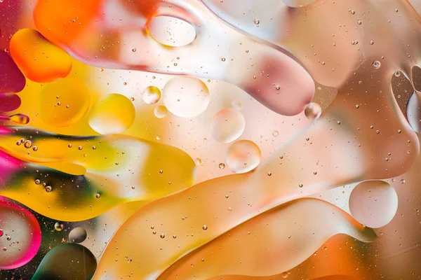 Su yüzeyindeki yağ damlacıklarının hareketine yakın çekim. Su yüzeyindeki yağ damlalarının renkli ve soyut makro arkaplanı