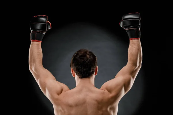 運動選手は黒い背景の後ろから見える運動選手の筋肉の体である腕を上げた — ストック写真