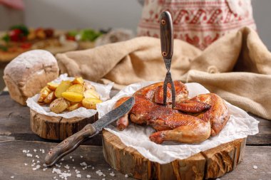İştah açıcı tavuk ve patates üzerinde ahşap spilah süsleyin. Özgün çatal ve çuval bezi Tekstil Natyurmort. Rustik.