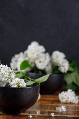 Kar-beyaz leylak çiçek ve siyah zarif bardak. Yakın çekim.