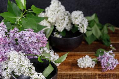 Kar-beyaz ve mor eflatun çiçekler ve ahşap arka plan üzerinde siyah zarif bardak. Yakın çekim.