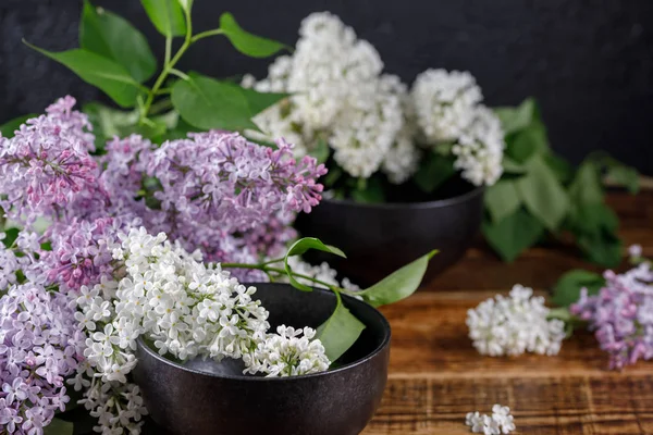 Güzel beyaz ve mor çiçekler Lila ve siyah zarif bardak. Natürmort ahşap arka plan üzerinde. Yakın çekim.
