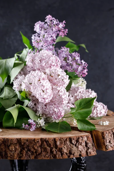 Kar-beyaz ve pembe ve mor tahtadan yapılmış zarif masa üstü üzerinde üç renk leylak ağacının güzel çiçekler. Natürmort ahşap arka plan üzerinde.